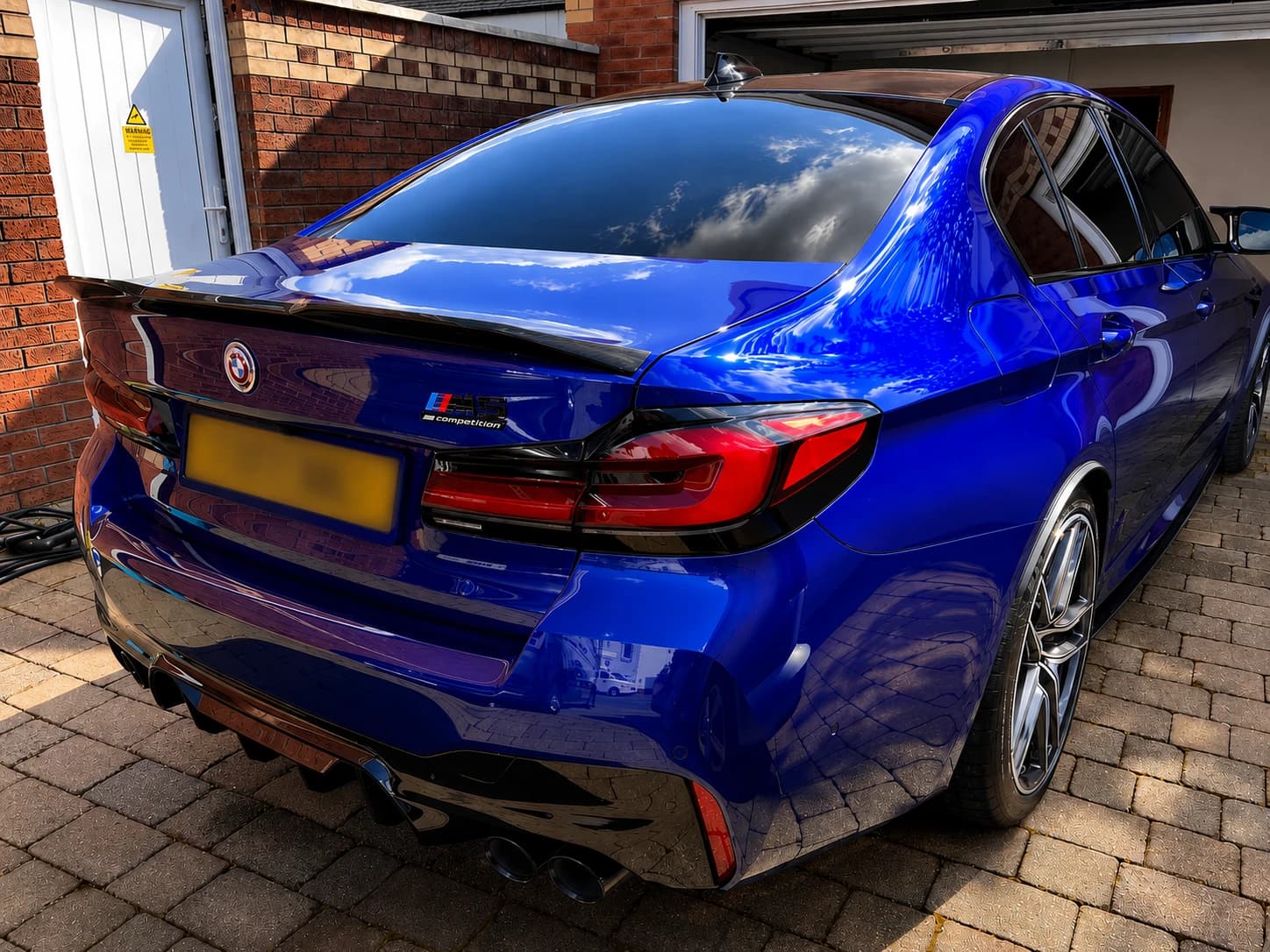 Glossy blue BMW M5 Competition presented after new-car preparation and protection, with the registration plate blurred.