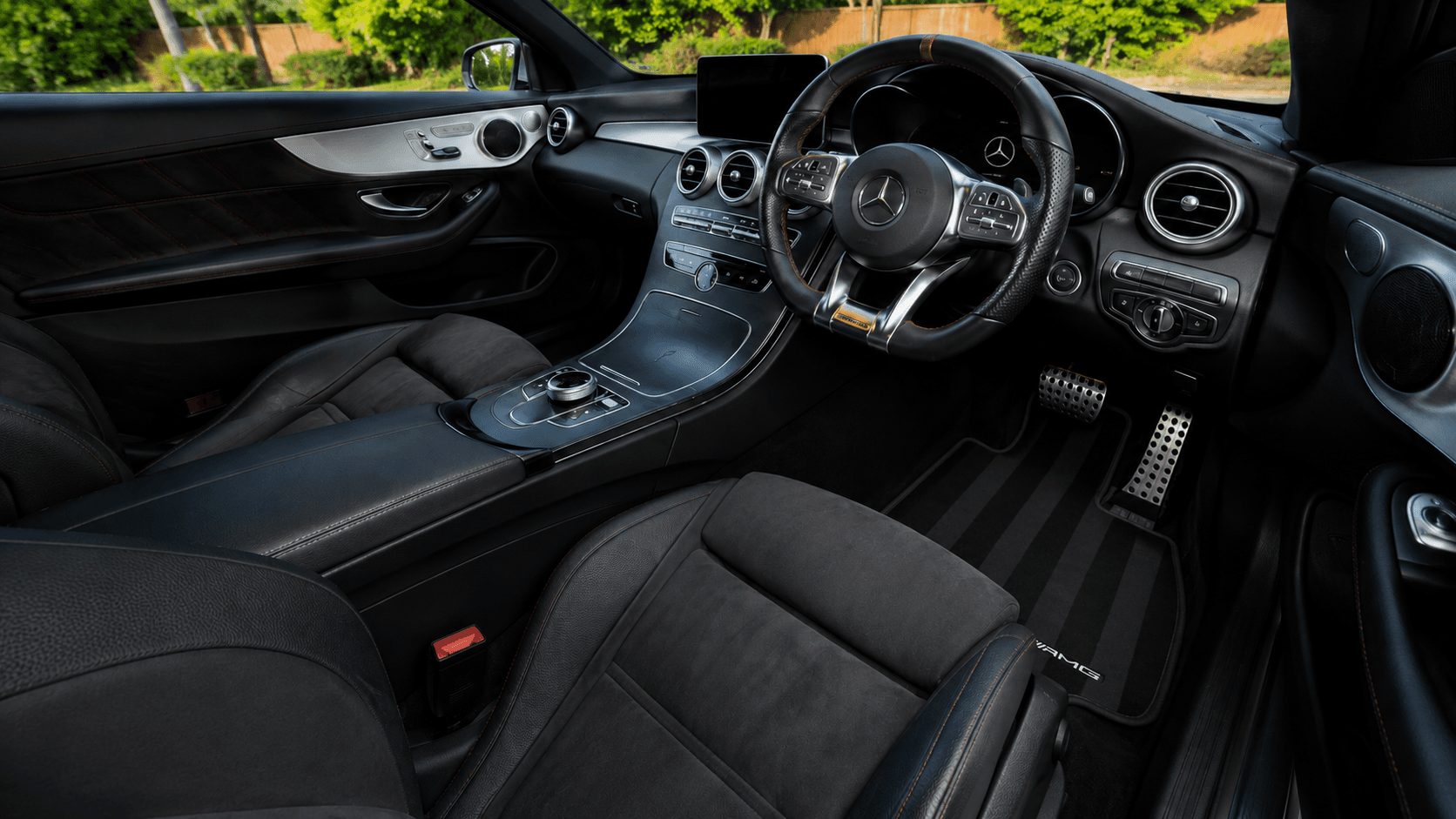 Wide finished view of a detailed right-hand-drive Mercedes-AMG cabin showing the dashboard, steering wheel, centre console, front seats, footwell and AMG mat.